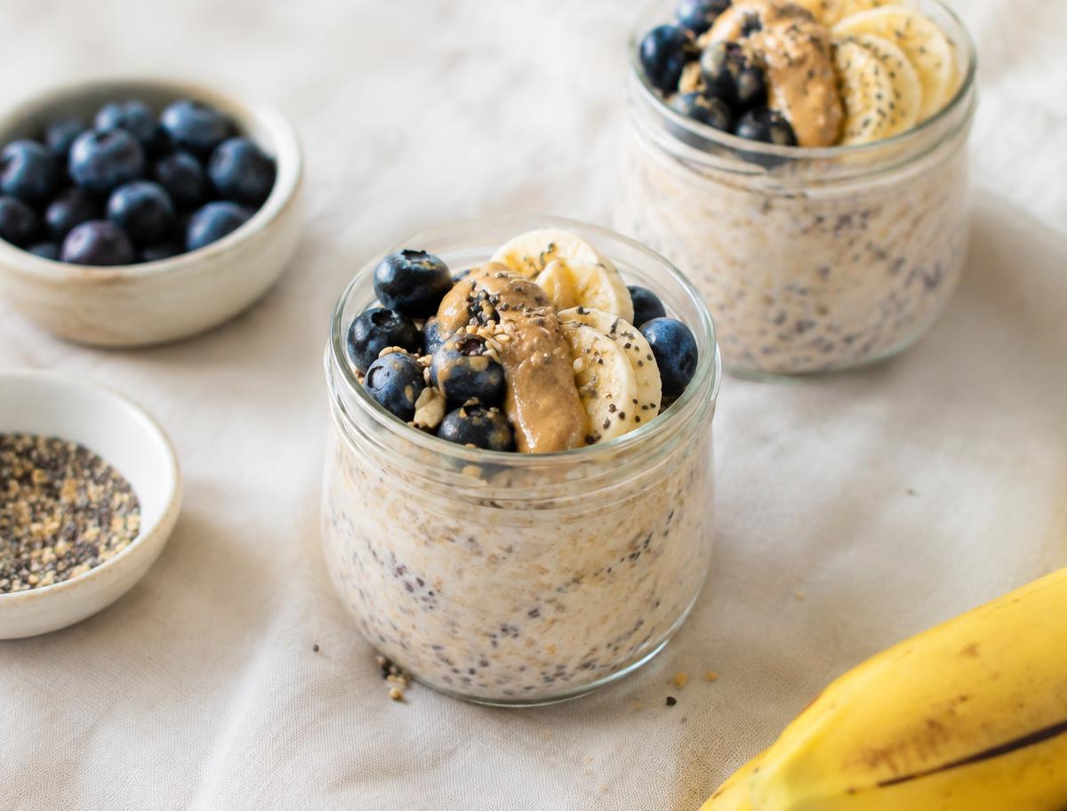 Overnight oats in glass jars topped with blueberries, banana and nut butter